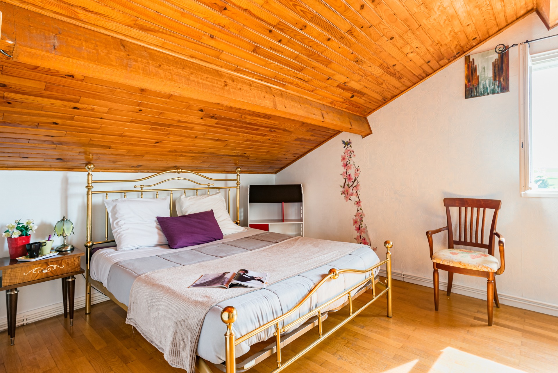 Chambre Iris de la Suite Perle : lit en laiton et plafond en bois, ambiance chaleureuse et cosy