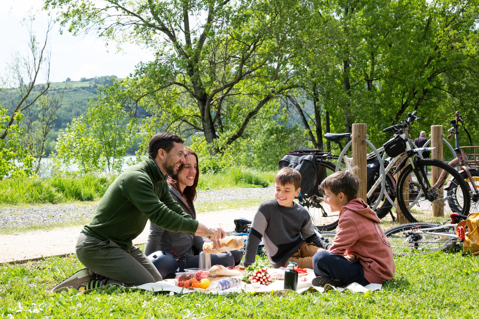 Couple avec enfants au premier plan en pause pique-nique lors d'une balade à vélo sur la ViaRhôna à Ampuis