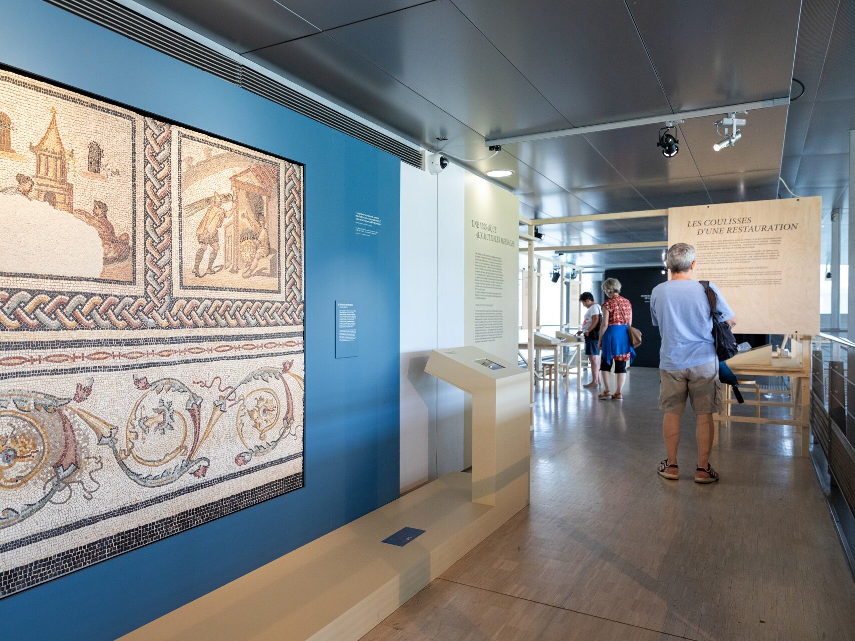 Pièce dans le musée de Saint-Romain en gal. On voit une mosaïque et des explications sur l'exposition. Un homme est en train de lire 