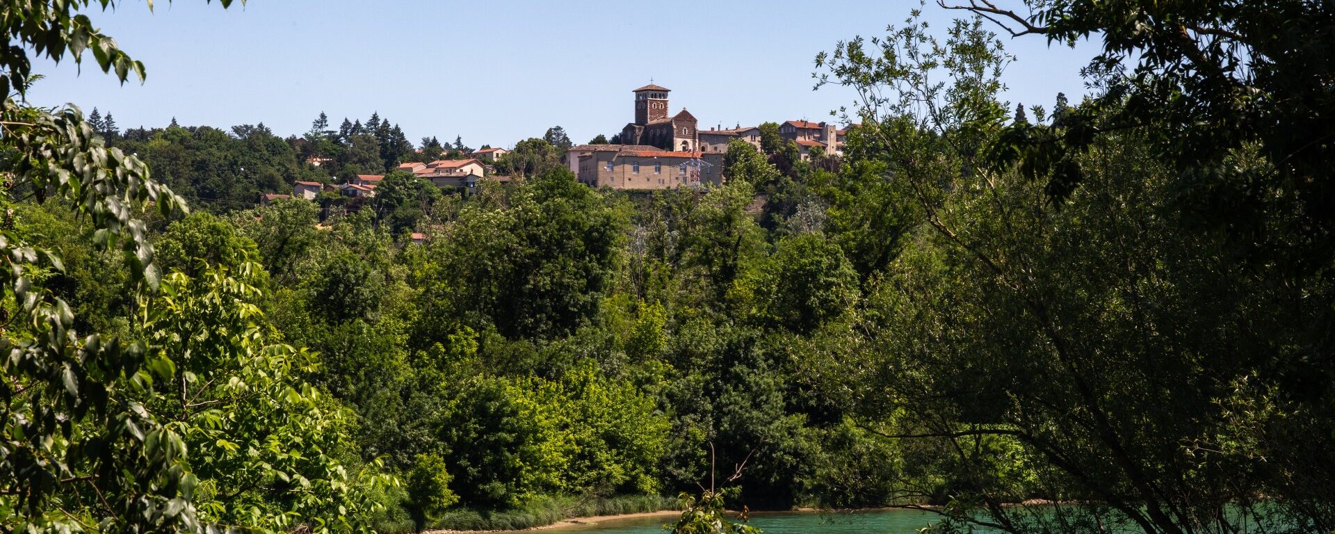 Vue sur le Rhône, avec au loin la colline et le château de la Porte à Ternay, avec des arbres encadrant la photo.
