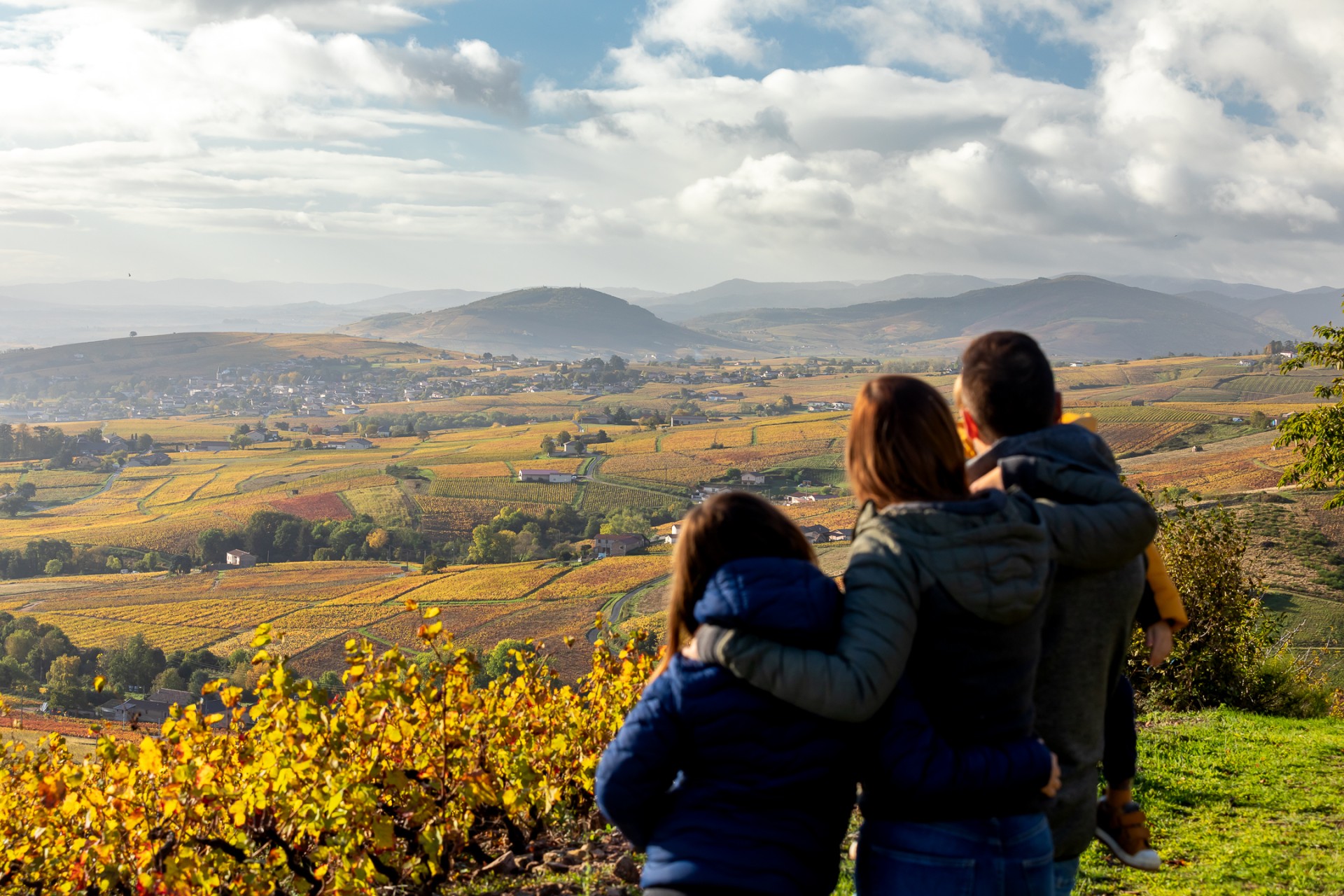 Une famille contemple le vignoble du Beaujolais aux couleurs de l’automne.